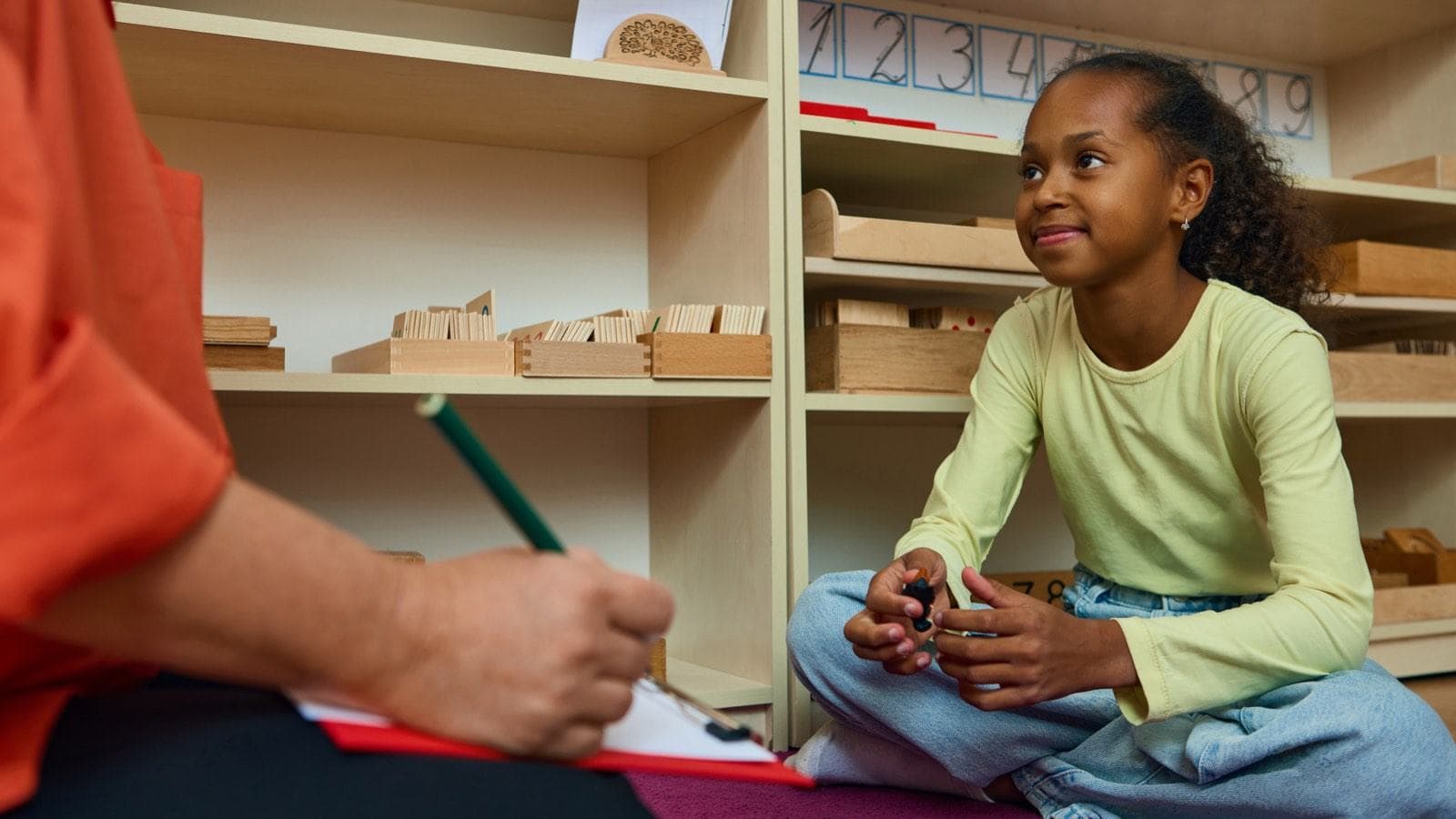 A teacher helping a girl at her desk in a classroom